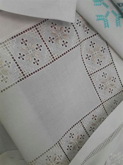 Some White Linens With Cross Stitch Designs On Them And One Is Folded