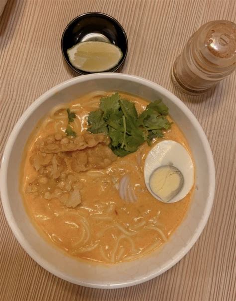 A White Bowl Filled With Soup And Garnishes On Top Of A Wooden Table