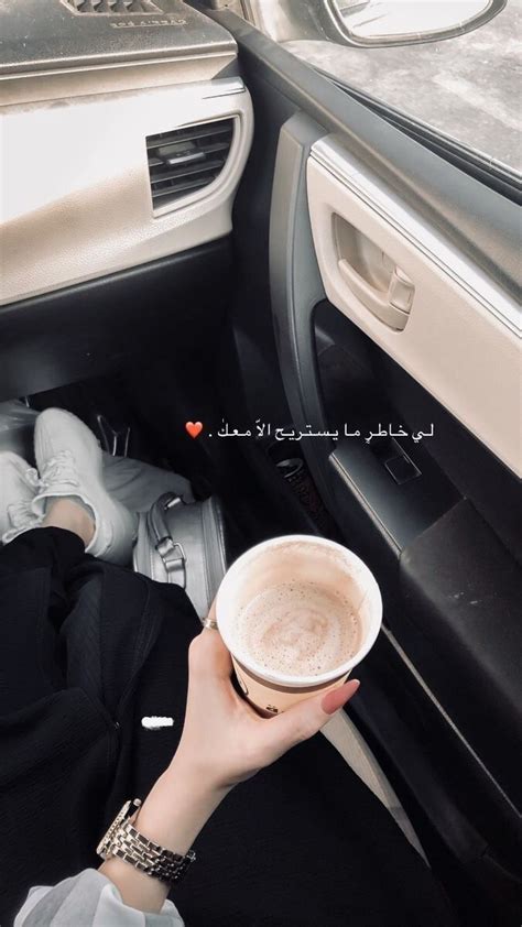 A Woman Holding A Cup Of Coffee While Sitting In A Car