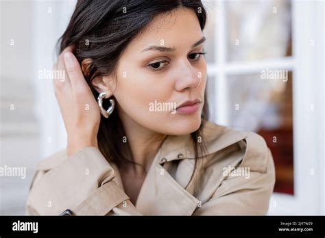 Portrait Of Brunette Woman In Beige Trench Coat And Hoop Earring