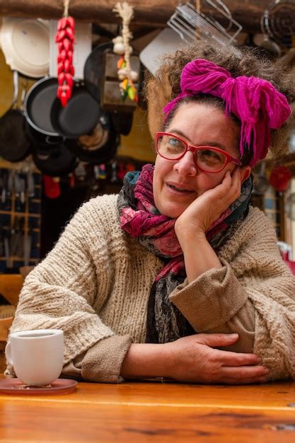 Mulher latina lenço na cabeça e óculos sentado em uma cozinha prestando atenção Foto Premium