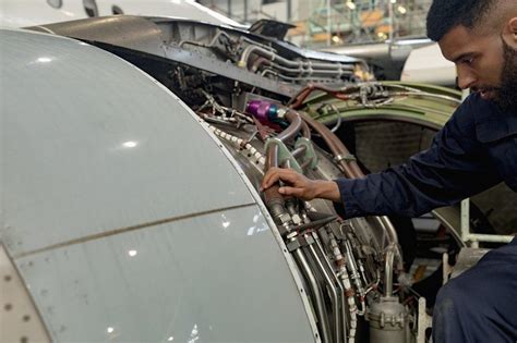 Aircraft maintenance engineer examining turbine engine of aircraft ...