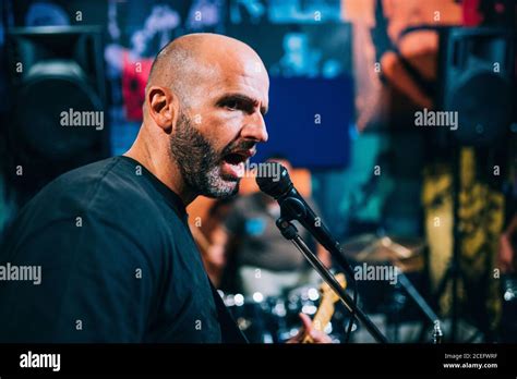 Side View Of Bald Man In Black T Shirt Standing Near Microphone On