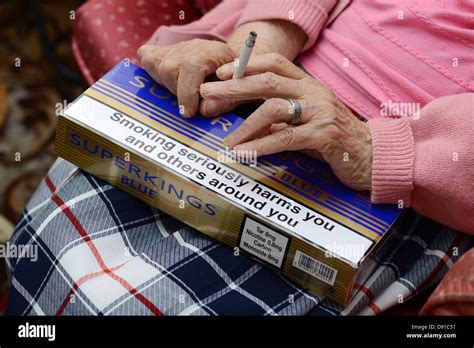 Carton Of Cigarettes With Hands Of Smoker Holding Cigarette Stock Photo