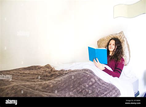 young woman lying in bed reading Stock Photo - Alamy