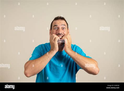Studio Portrait Of Scared And Shocked Dark Haired Mature Man Biting His