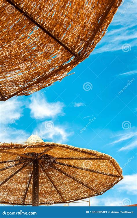 Parasol De Playa De La Paja De Wattled En Fondo Azul De Cielo Nublado