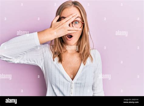 Beautiful Blonde Woman Wearing Casual Clothes And Glasses Peeking In Shock Covering Face And