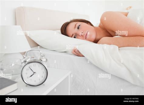 Beautiful Brunette Woman Awaking With A Clock While Lying On A Bed