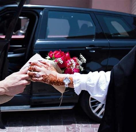 A Bride And Groom Holding Hands In Front Of A Black Suv With Red Roses