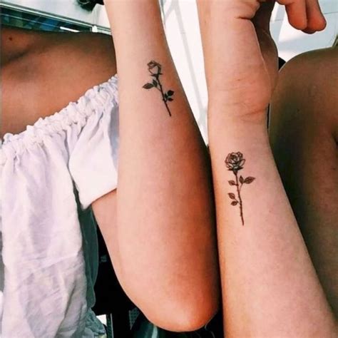 Two Women With Matching Tattoos On Their Arms Sitting Next To Each