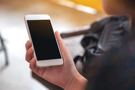 Manos sosteniendo un teléfono móvil blanco con pantalla de escritorio