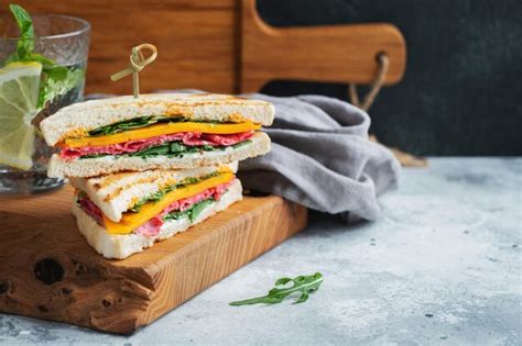 Dos sándwiches caseros con queso de salchicha y rúcula sobre un fondo