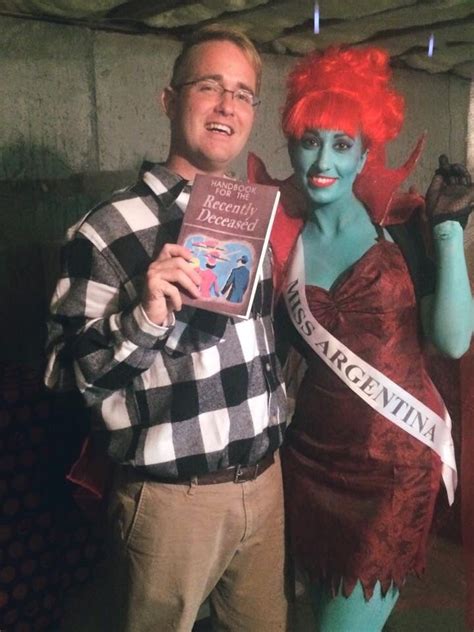 a man and woman dressed up in costumes posing for the camera with one holding a book