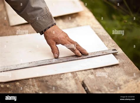 Senior Elderly Carpenter Using A Straightedge To Draw A Line On A Board