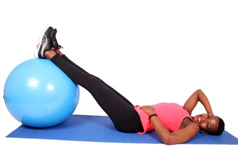 Attractive Woman Lying on Yoga Mat Placing Legs on Swiss Ball - High ...