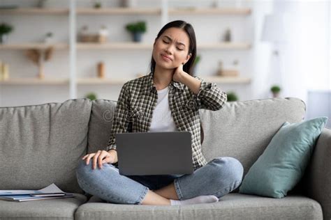 Upset Asian Woman Suffering From Neck Pain While Using Laptop Stock