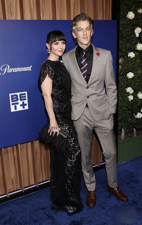 A Man And Woman Standing Next To Each Other In Front Of A Blue Carpeted