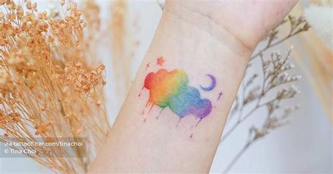 Watercolor rainbow cloud tattoo on the wrist.