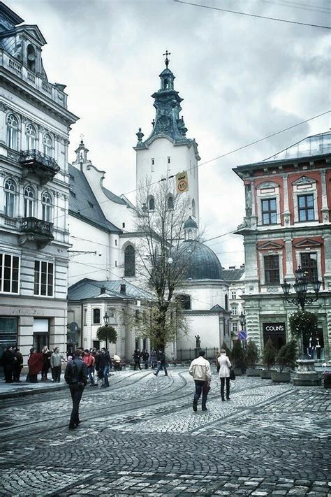 People Are Walking Around In An Old European Town With Cobblestone