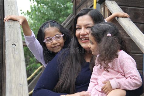 Mother With Two Brunette Latina Daughters Play On Playground Equipment And Spend Time Together
