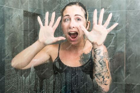 Belle Femme En Vêtements Mouillés Pose Ses Mains Sur Le Verre Sous La Douche Photo Premium