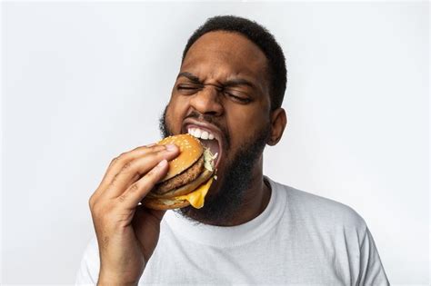 African Man Biting Burger Enjoying Junk Food Over White Background | Frases para whatsapp ...