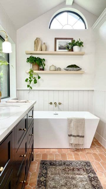 A White Bath Tub Sitting Under A Window Next To A Sink