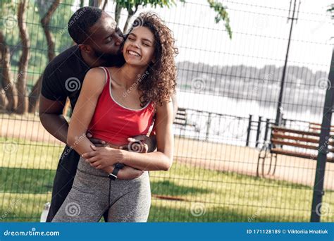 Outdoors Activity African Couple Standing On Court Hugging Guy Hkissing Girl Cheerful Stock