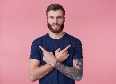 Chico joven de barba roja frunciendo el ceño engañado con los dedos