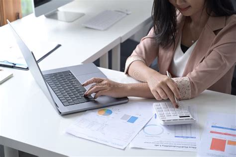 Busy Businesswoman Working On Laptop Computer And Using Calculator At