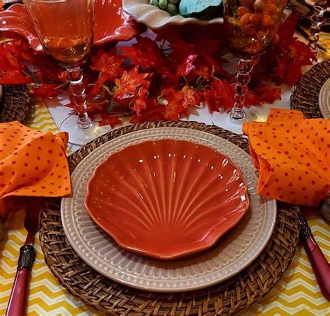 The Table Is Set With Orange Plates And Napkins