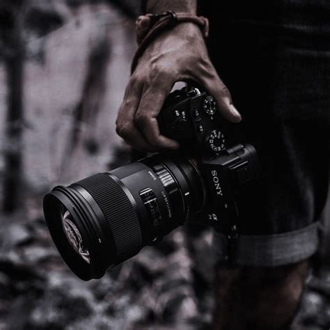 A Person Holding A Camera In Their Hand With The Lens Attached To His