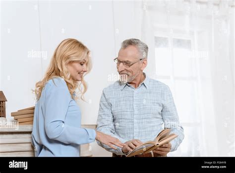 Mature Woman And Man Reading Book Together By Window In Light Room Stock Photo Alamy