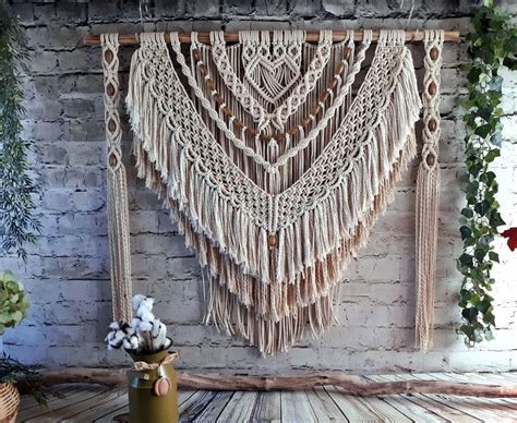 The Wall Hanging Is Made With Macrame And Tassels Along With Flowers