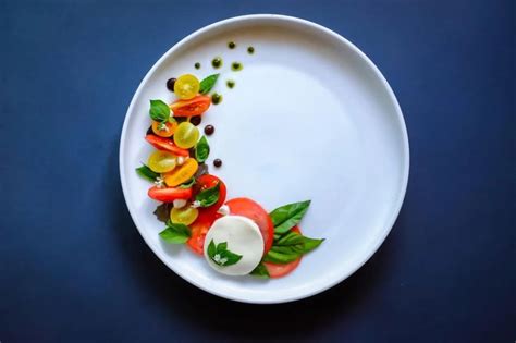 A White Plate Topped With Veggies On Top Of A Blue Table Next To A Knife