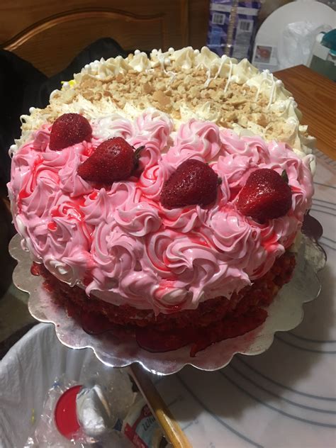 A Cake With White Frosting And Strawberries On Top Is Sitting On A Table