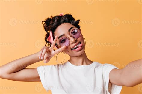 Smiling mixed race girl showing peace sign. Cute young woman taking ...