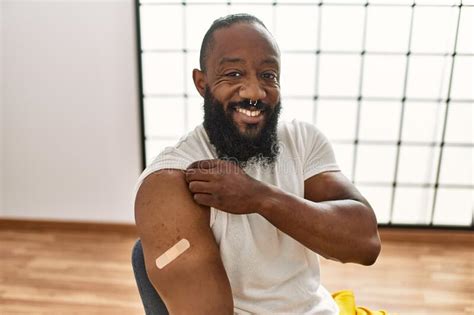 African American Man Getting Vaccine Showing Arm With Band Aid Looking