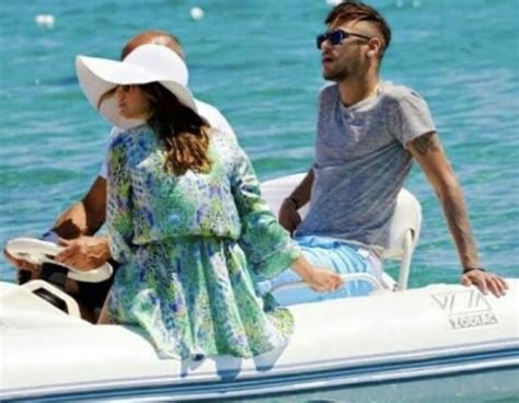 A Man And Woman Riding On The Back Of A White Boat