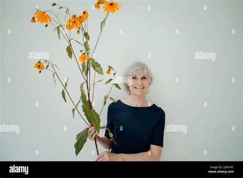 Smiling Senior Woman With Twig Standing Against White Background Stock