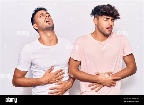 Jeune gay couple portant des vêtements décontractés avec main sur l estomac parce que la nausée