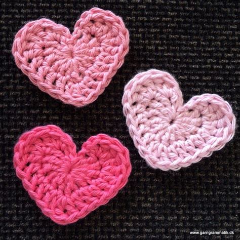 Two Crocheted Hearts Sitting Next To Each Other On Top Of A Black Surface