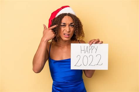 Joven mujer transexual latina celebrando el año nuevo aislado sobre fondo amarillo mostrando un