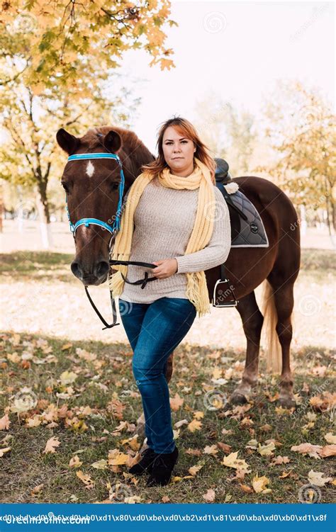 Woman Holds A Horse By The Reins Horseback Riding In The Autumn Forest