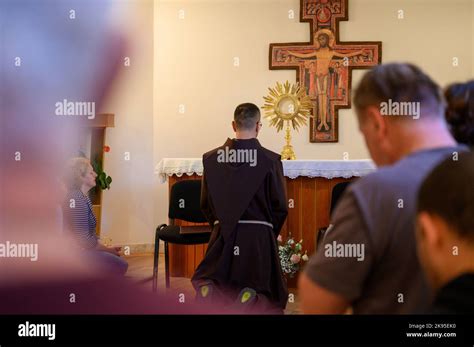 A Franciscan Friar With The Faithful Adoring Jesus In The Most Blessed Sacrament During Prayer