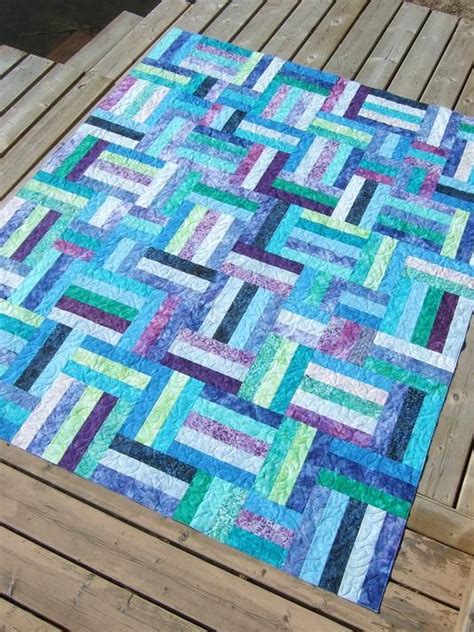 A Blue And Green Quilt Sitting On Top Of A Wooden Deck