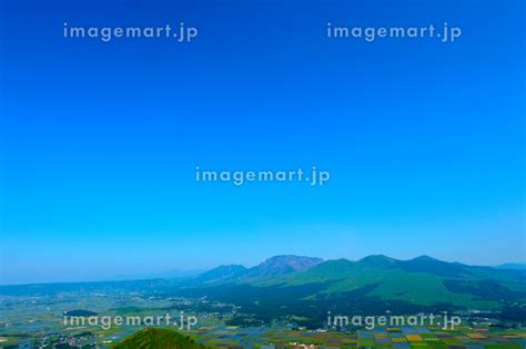 阿蘇外輪の草原からパッチワークの田園風景と雄大な阿蘇五岳を望むの写真素材 [185376975] イメージマート