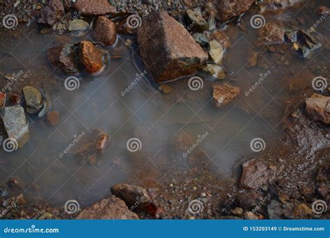 A Still Life Picture Of A Puddle With Rocks Which Shows Peace And