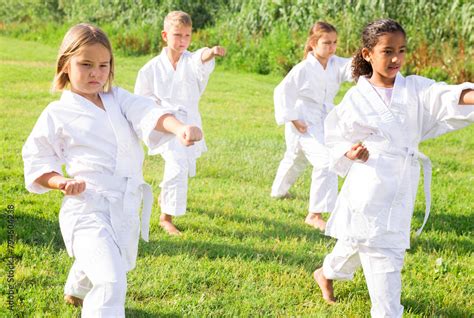 Barefoot kids doing kata during outdoor karate training. Stock Photo | Adobe Stock